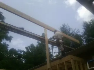 Carpenter setting a ridge beam over a new addition frame — Ice Dam Removal by Roofing Brothers in Stuart