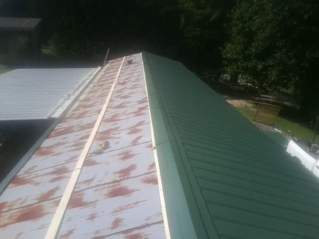 Old rusted panels beside newly installed green metal roofing — Wind Damage Roof Repair by Roofing Brothers in Stuart