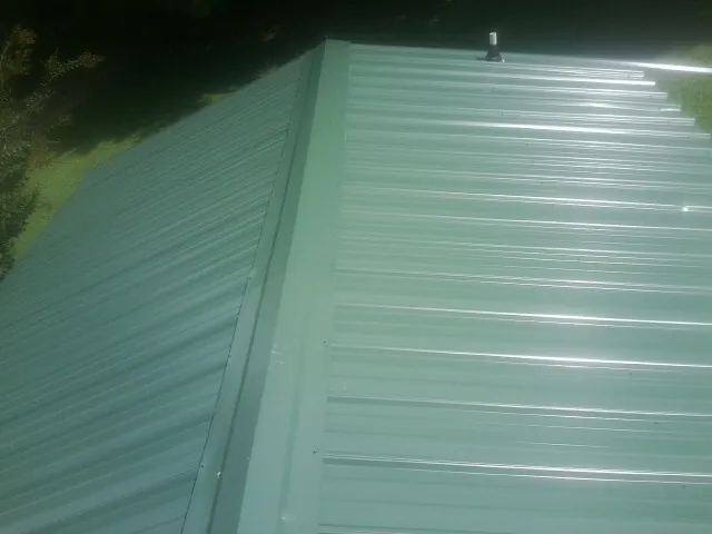 New green metal panels meeting at the ridge of a roof — Flat Roof Repair work by our crew in Stuart
