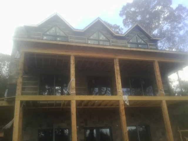 Dormers and porch framing on a large log home under construction — Roof Coating work by our crew in Stuart
