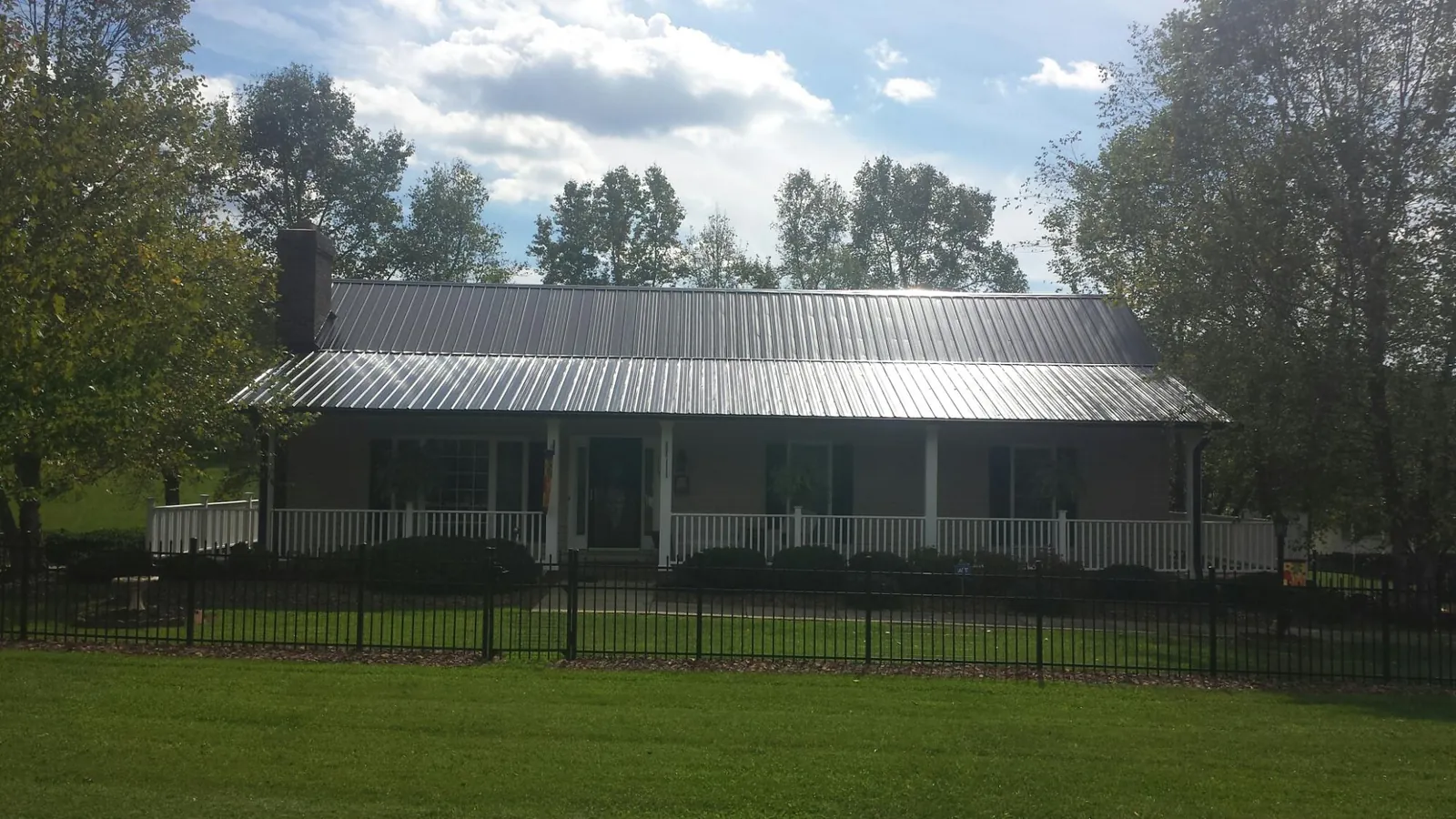 Gray metal roof on a brick ranch with a full width front porch — Gutter Guard Installation work by our crew in Stuart