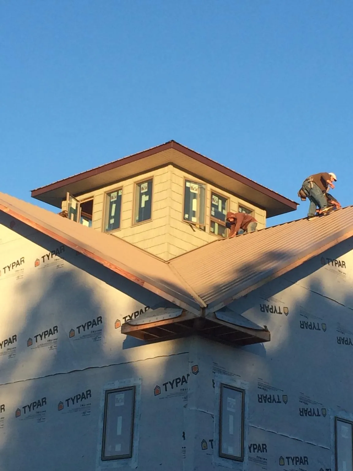 Roofers working around a rooftop cupola on a new metal roof at sunset — Roof Waterproofing in Stuart by Roofing Brothers